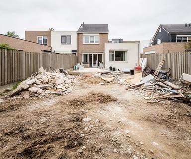 Achtertuin in Nuth met bouwafval en kale grond na werkzaamheden aan de woning